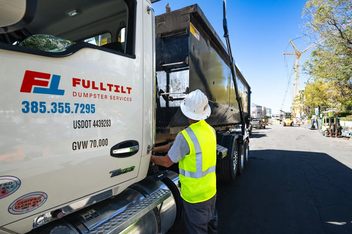 Full Tilt driver beside a branded dumpster truck