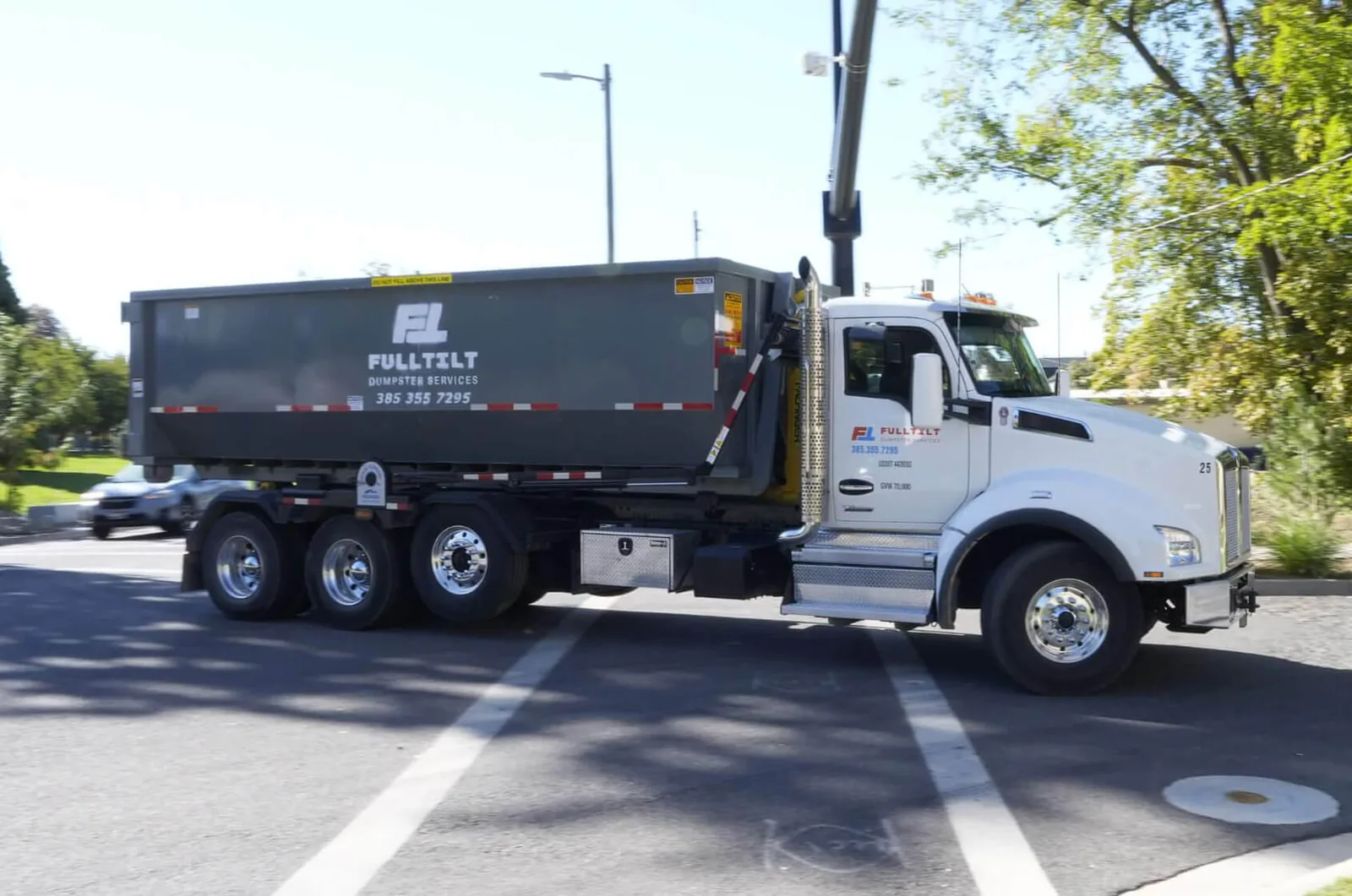 Full Tilt branded truck carrying a roll-off dumpster